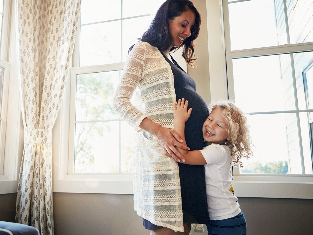 Young child embracing pregnant mother