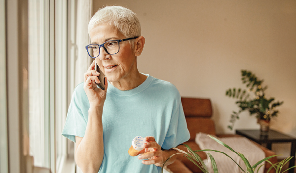 Older woman on phone holding Rx bottle
