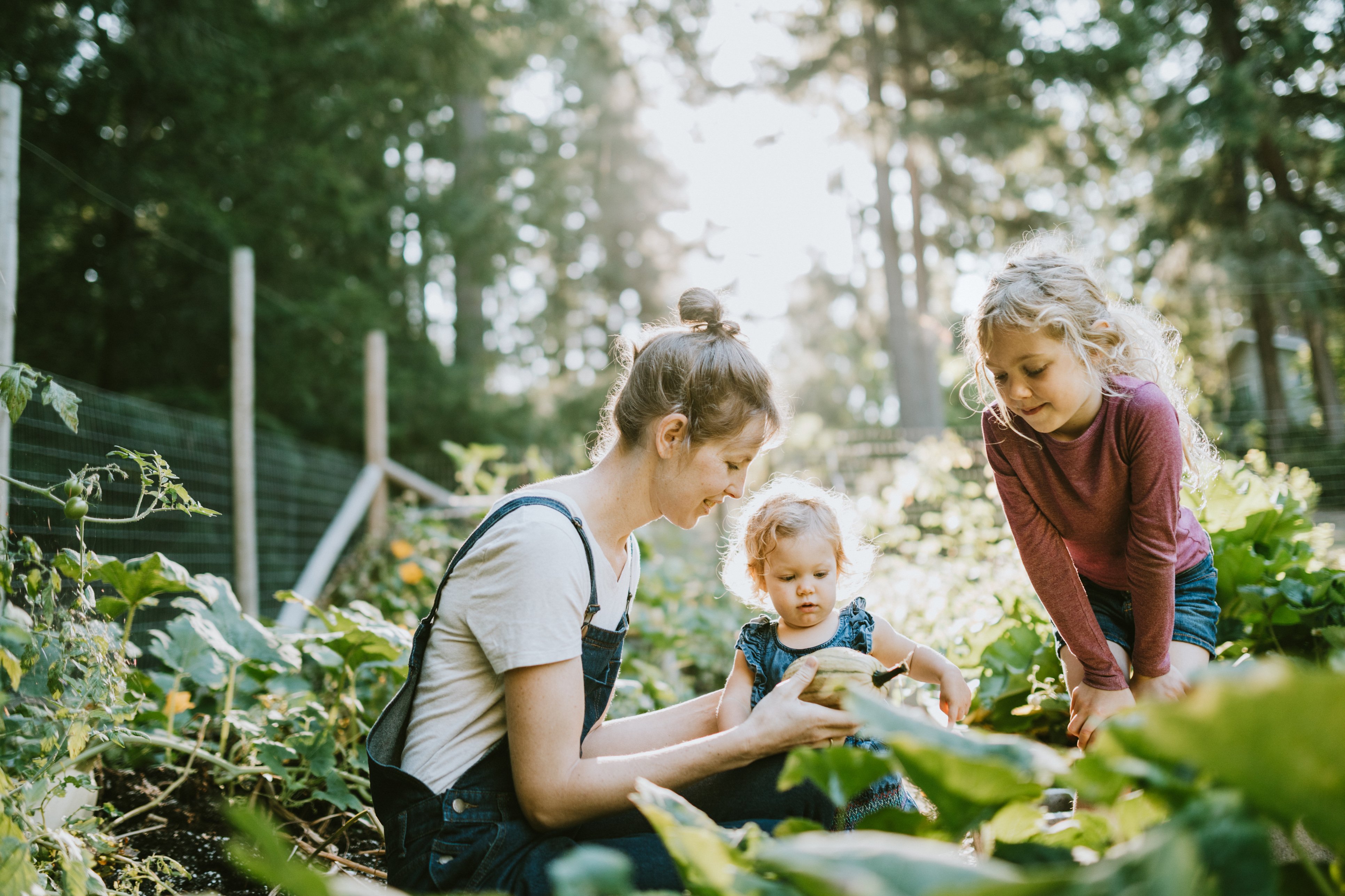 Mom with two small girls working in home garden