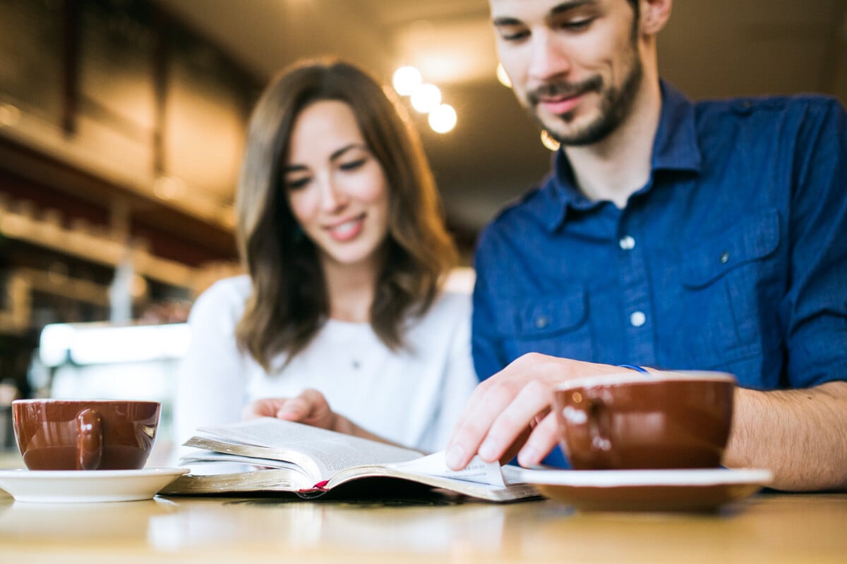 Young couple reading bible at coffee shop